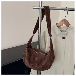 Detail van donkerbruine suède hobo-tas met brede schouderriem en metalen rits
