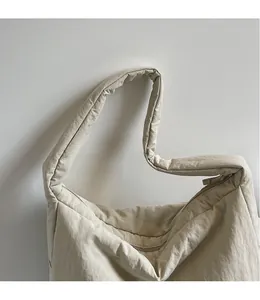 Detail der beigen Nylon-Umhängetasche mit weichen Falten und glattem Schultergurt