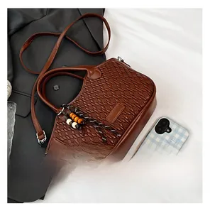 Detail view of woven leather texture on a brown bucket bag with bead tassel charm
