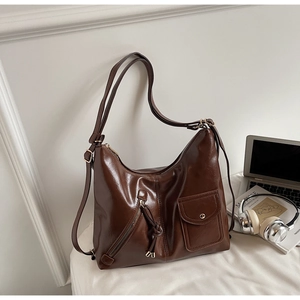 Detail of dark brown vintage leather shoulder bag with functional zippers and pockets