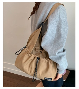 Macro detail of khaki drawstring tote bag featuring black and white cord and fashion label