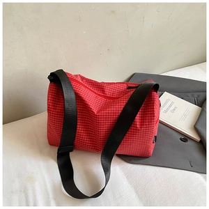 Detail of red checkered cylinder crossbody bag with durable nylon and wide black strap