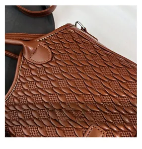 Close-up of brown leather bucket bag featuring detailed woven scale-like texture