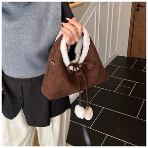 Détail du sac à main en daim marron foncé avec poignée en peau de mouton et nœud serré