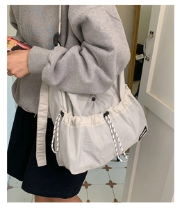 Detail of cream drawstring tote bag showing ruched texture and adjustable wide shoulder strap