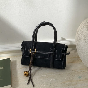 Detail of black suede handbag with contrast stitching, gold hardware and bell charm