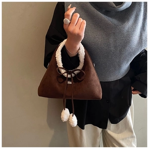 Détail du sac à main en daim marron avec poignée en laine blanche et pompons décoratifs
