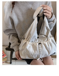 Detail of cream drawstring tote bag showing the textured fabric and fashion label