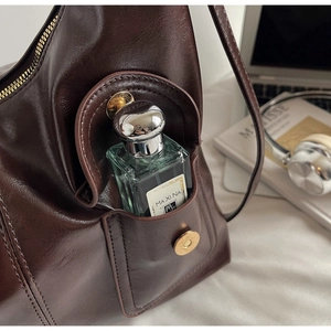 Macro shot of dark brown leather bag showing side pocket with perfume bottle storage