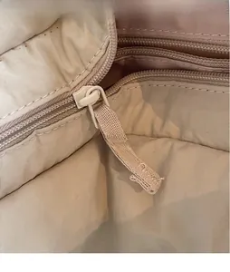 Detailansicht des beigen Stofffutters und des langen Reißverschluss-Ziehers der Tasche