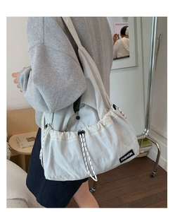Detail of white drawstring crossbody bag featuring contrast cord and FASHION woven label