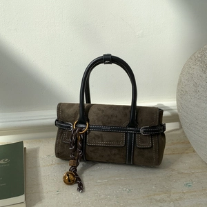 Detail of dark olive suede square bag with braided charm and leather handle