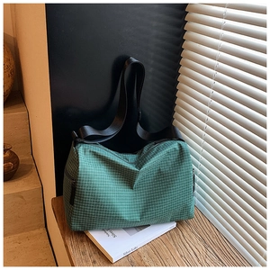 Detail of green checkered shoulder bag with black strap and side zipper pocket