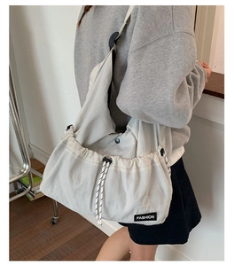 Close-up of drawstring closure detail on light gray nylon crossbody tote bag