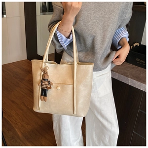Detail of a large cream white leather tote bag featuring a cute rabbit charm accessory