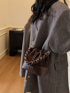 Dark brown leather bucket bag with braided chain handle and drawstring closure