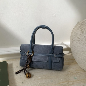 Detail of blue suede handbag with metal ring, decorative charms and PAN'TOR logo on the side
