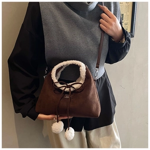 Détail du sac en daim marron avec bordure en simili mouton et pompons en peluche
