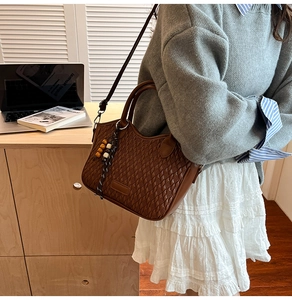 Detail of dark brown bucket bag with woven texture and decorative beaded wood tassel