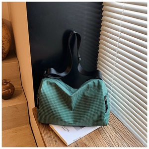 Detail of green plaid tote bag showing waterproof fabric and adjustable nylon strap