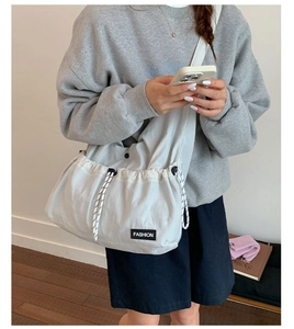 Detail of drawstring crossbody bag showing nylon material and Fashion logo label