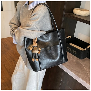 Detail of black faux leather tote bag with a cute rabbit pendant and textured surface