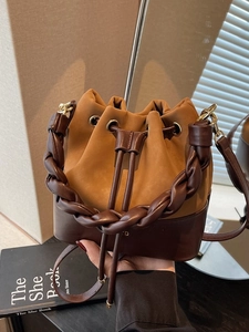 Two-tone leather bucket bag with braided handle and adjustable strap in retro style