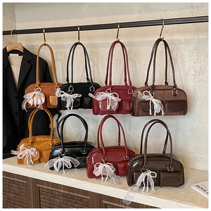 Close-up of stylish handbags in matte and glossy textures with elegant bow charms