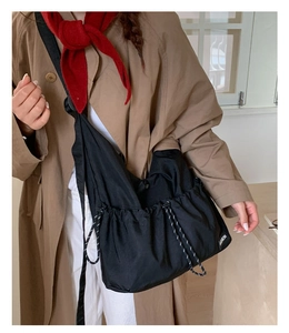 Detail of black nylon crossbody bag featuring drawstring design and Fashion textile label