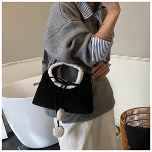 Détail du sac en daim noir avec garniture en fausse fourrure blanche et pompons
