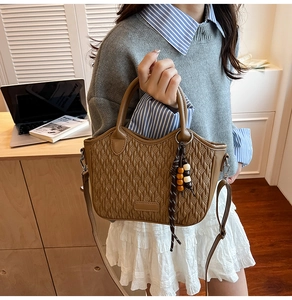 Detailed close-up of brown woven texture bucket bag with wooden bead charm in a lifestyle setting