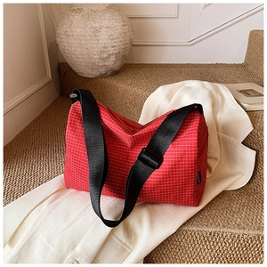 Detail of red and white checkered nylon bag with black strap on a cozy indoor setting