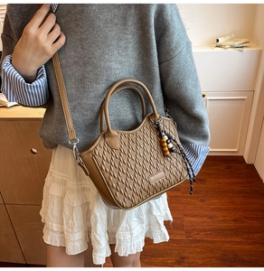 Detail of tan faux leather bucket bag with woven texture and wooden bead charm accessory