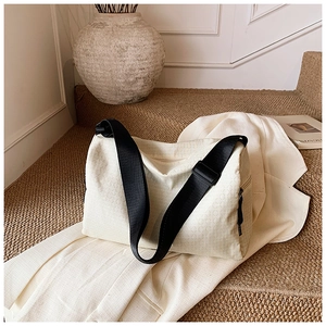 Close-up of cream quilted pillow bag with black adjustable strap in a stylish setting