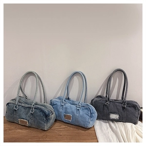 Three denim bowling bags in gray and blue washes with frayed metal tag on wooden table