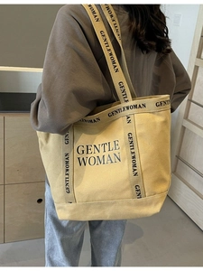 Grande borsa tote in tela beige con scritte nere vista da un'angolazione di 45 gradi