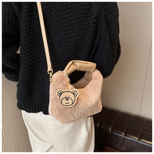Détail d'un sac à main beige en fausse fourrure avec breloque ours et bandoulière