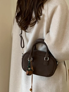Deep brown vintage Boston handbag with leather flower charm shown with a model