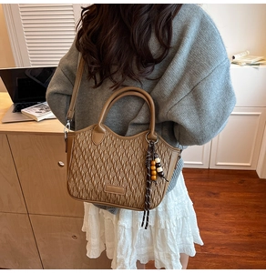 Detailed close-up of dark brown woven texture bucket bag with wooden bead charm detail