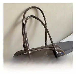Detail showing high-quality deep brown glossy leather texture and silver zipper of tote bag