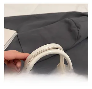 Détail des poignées en cuir blanc avec coutures précises et fermeture éclair argentée