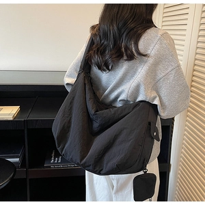 Detailansicht der schwarzen Umhängetasche aus Nylon mit Rückansicht und Fall am Model