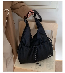 Detail of black canvas tote bag with drawstring closure and Fashion label on chair
