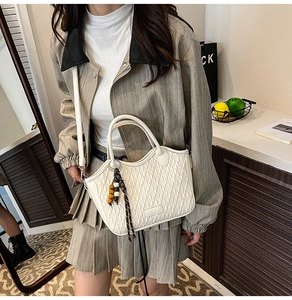 Close-up of woven texture on cream bucket bag with decorative wooden beaded tassel