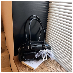 Detail of black glossy leather bag featuring white lace bow and faux pearl accents