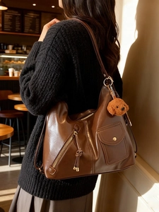 Vintage brown shoulder bag with plush dog charm and multi-pocket design for daily use