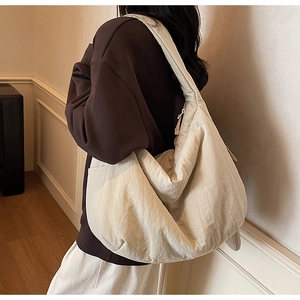 Detail der minimalistischen cremefarbenen Hobo-Tasche mit weichem Stoff und lässigem Design