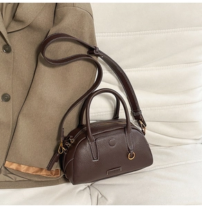 Close-up of dark brown pebble leather bowling bag with fine white stitching and gold hardware