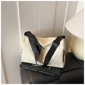 Detail of cream plaid shoulder bag with wide black strap and textured woven surface