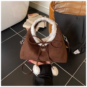 Détail du sac en daim marron avec bordure en laine mouton blanche et nœud à pompons